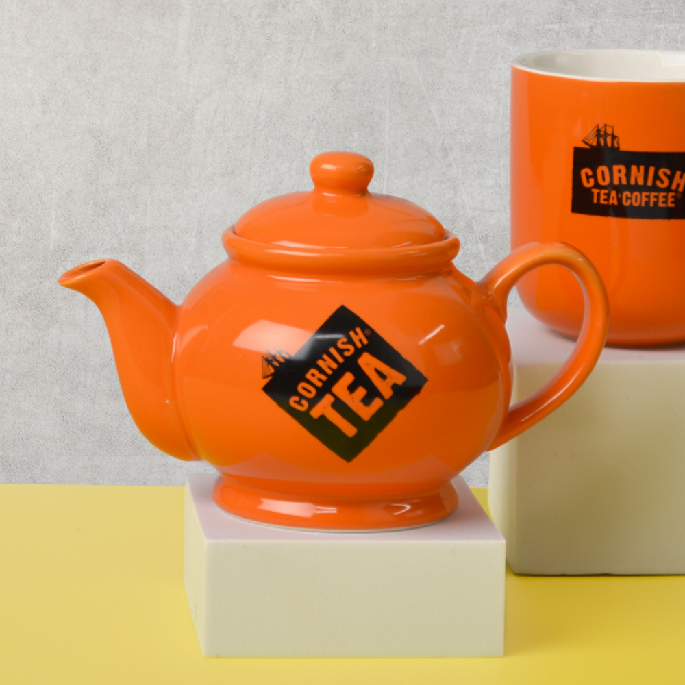An image of a Cornish Tea teapot and an orange Cornish Tea & Coffee mug.